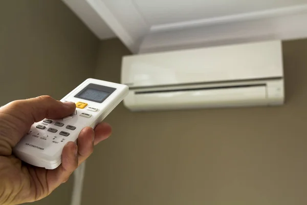 Mão segurado interruptor de controle de ar condicionado em casa — Fotografia de Stock