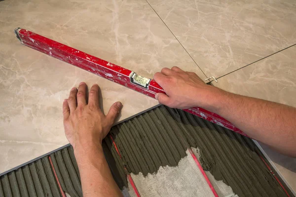 Azulejos e ferramentas para tigre. Trabalhador mão instalar pisos. Melhoria da casa, renovação - adesivo de piso de cerâmica, argamassa, nível . — Fotografia de Stock