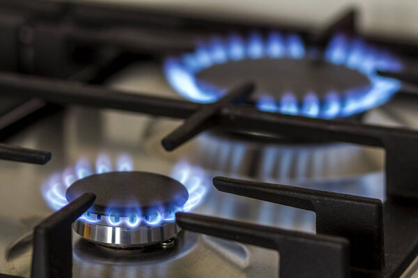 Природный газ горит на кухне газовая плита в темноте. Панель из стали с газовой горелкой на черном фоне, крупным планом
