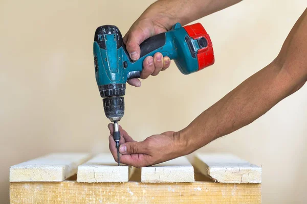 La mano del trabajador atornilla el tornillo en la tabla de madera con los cordones — Foto de Stock