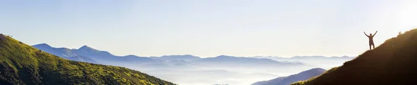 Panorama de jovem homem bem sucedido silhueta caminhante braços abertos no pico da montanha . — Fotografia de Stock