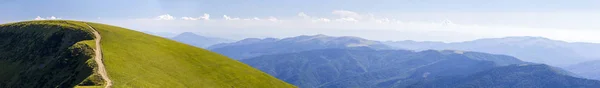 Панорама зеленых холмов в летних горах с гравийной дорогой для — стоковое фото
