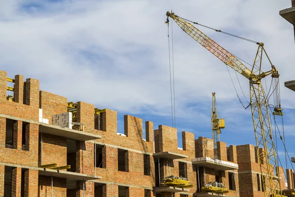 Baustelle eines neuen Mehrfamilienhauses mit Turmdrehkränen vor blauem Himmel. Wohngebietsentwicklung. Wachstumskonzept für Immobilienprojekt. — Stockfoto