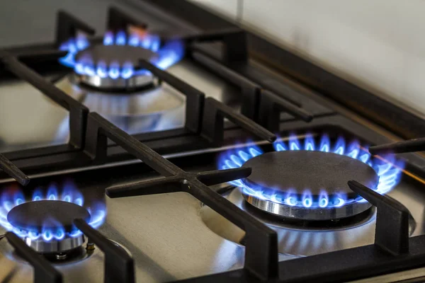 Brûlure de gaz naturel sur cuisinière à gaz de cuisine dans le noir. Panneau en acier avec brûleur à anneau de gaz sur fond noir, prise de vue rapprochée — Photo