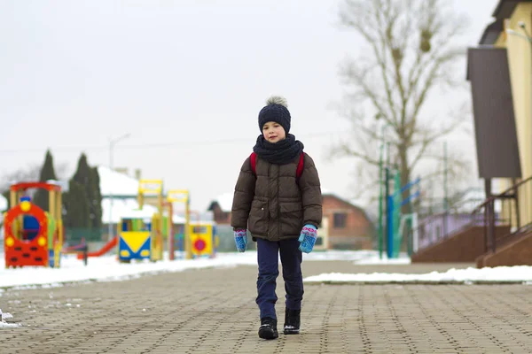 Jongetje wandelen in het park. Kind gaan voor een wandeling na school met een schooltas in de winter. Kinderen activiteit buiten in de frisse lucht. Gezonde manier van leven concept. — Stockfoto