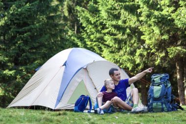 Tatil kamp. Baba oğlu bir şey sonra Orman gezici ve açık hava etkinlikleri'da yürüyüş çadır yakınındaki dinlenme alarak mesafe gösterir. Mutlu aile ilişkileri ve sağlıklı yaşam tarzı.