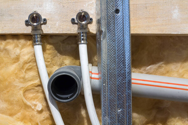 Water pipes made of polypropylene in the wall, plumbing in the house. Installation of sewer pipes in a bathroom of an apartment interior during renovation works. Gray plastic drain pipe for used water