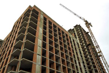 Yeni bir modern konut ev bina inşaat altında zemin görünümünü. Gayrimenkul geliştirme kavramı. Çok hikaye ev tuğla ve beton. İş yerinde inşaat site Vinçler.