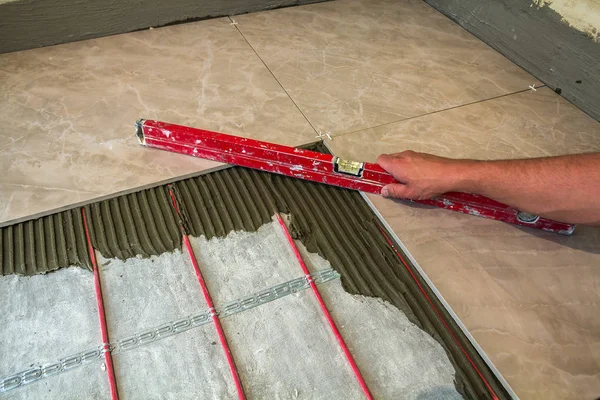 Ceramic tiles and tools for tiler. Worker hand installing floor — Stock Photo, Image