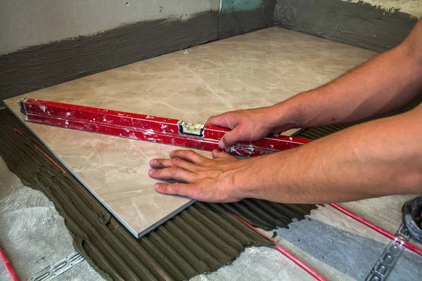 Keramische tegels en hulpmiddelen voor de tegelzetter. Werknemer hand installeren vloer — Stockfoto