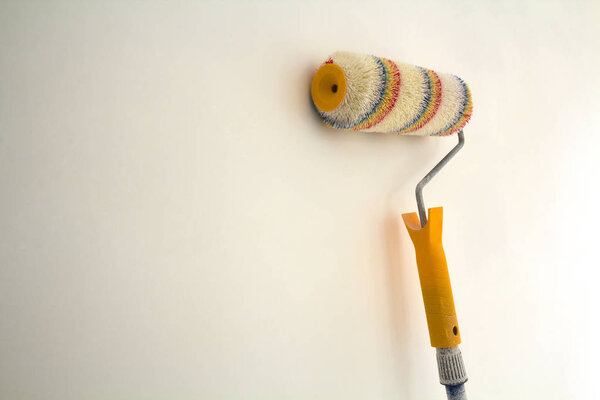 Paint roller brush near wall in renovated room interior isolated on white background. Renovation and DIY concept.