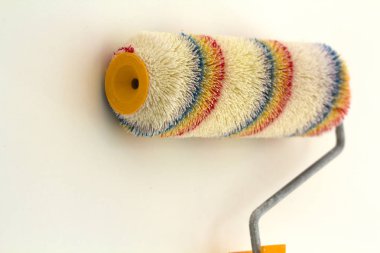 Beyaz arka plan üzerinde izole yenilenmiş oda iç duvarının yakınında rulo fırça boya. Yenileme ve DIY kavramı.