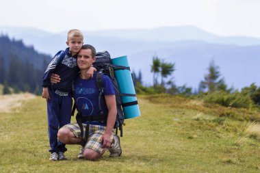 Baba ve oğul birlikte doğal hiking sırt çantaları ile yeşil dağlar yaz. Baba ve çocuk ayakta zevk dağ manzaralı manzara. Aktif yaşam tarzı, aile ilişkileri, hafta sonu etkinlik kavramı.