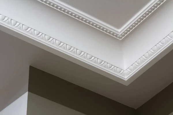 Ornamental white molding decor on ceiling of white room close-up detail. Interior renovation and construction concept. — Stock Photo, Image