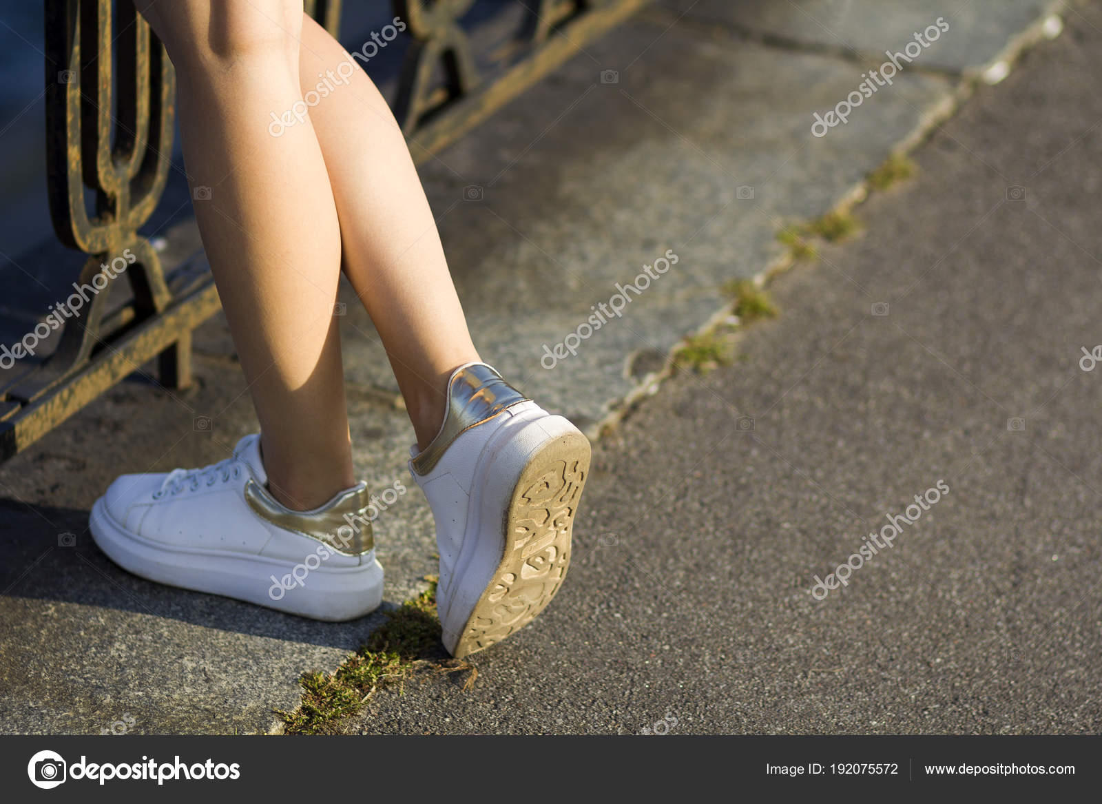 Close up of beautiful slim legs of young girl in white sneakers