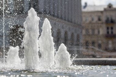 Soğuk temiz pırıl pırıl taze su şeffaf bir çeşmenin yüksek güçlü coşma yakın çekim. Beyaz köpük ve şehir arka plan üzerinde damlacıklar.