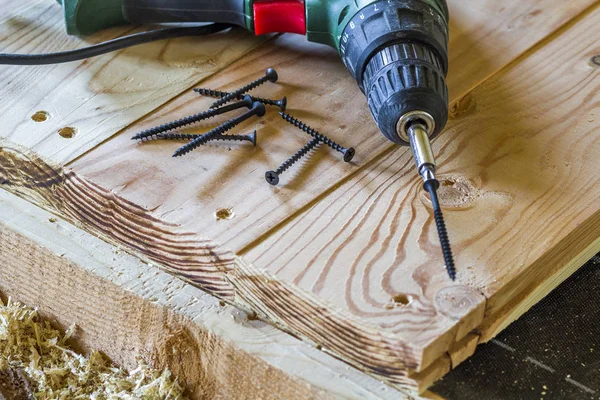 Close up de chave de fenda elétrica com alguns parafusos que colocam no velho — Fotografia de Stock