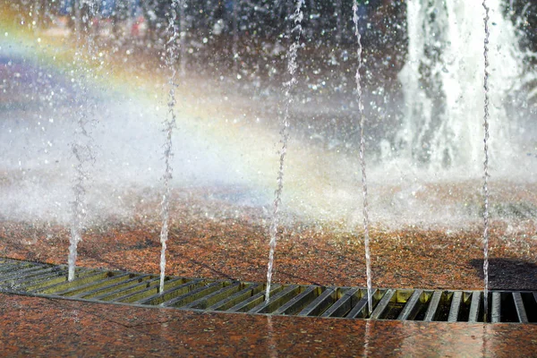 Close up of beautiful city fountain. Splashing upward crystal thin streams of clear cool transparent water, shiny droplets. Multicolored blurred rainbow, recreation area. — Stock Photo, Image