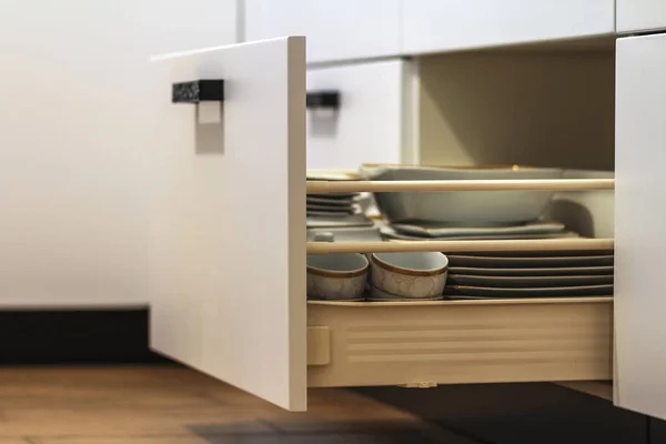 Open kitchen drawers with plates and cups dishes