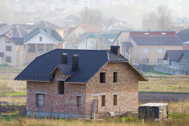 Çatı ve windows açıklıklar arka planda uzak şehrin varoş mahallesinde döşeme ile yeni geniş tuğla iki hikaye konut ev. Rel, ipotek ve İnşaat Emlak Emlak.