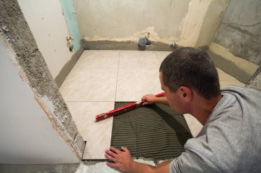 Ev geliştirme - düzey karo zemin döşeme ile tamirci döşer. Tadilat ve inşaat kavramı.