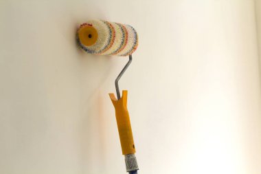Beyaz arka plan üzerinde izole yenilenmiş oda iç duvarının yakınında rulo fırça boya. Yenileme ve DIY kavramı.