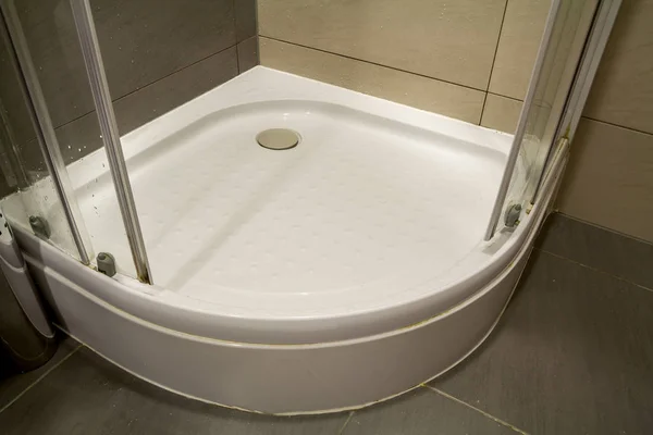 Dettaglio primo piano della nuova cabina doccia bianca pulita e moderna con gocce d'acqua sulla porta in vetro trasparente e belle piastrelle di ceramica beige chiaro sul pavimento e sulle pareti. Comfort e concetto di igiene . — Foto Stock