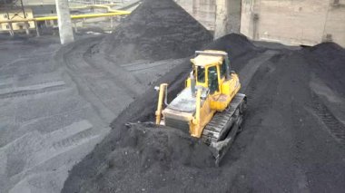 Buldozer çekici termoelektrik santralinin ikmal sahasında siyah kömür topluyor..