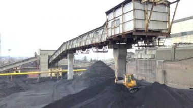 Buldozer çekici termoelektrik santralinin ikmal sahasında siyah kömür topluyor..