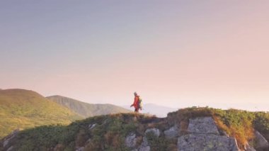 Karpat dağlarında dağ yolunda yürüyen turuncu ceketli bir sırt çantası ile Turist yürüyüşçü.