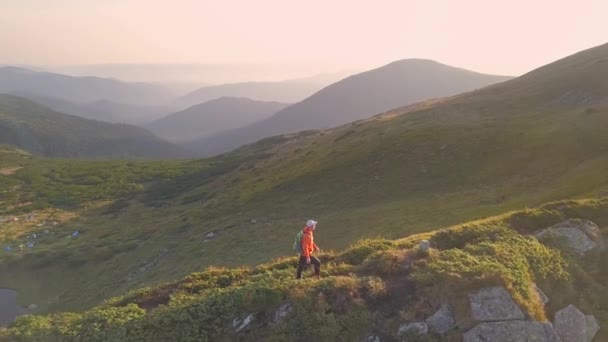 游客徒步旅行者背着一个背包 穿着橙色夹克走在喀尔帕西亚山脉的山路上 — 图库视频影像