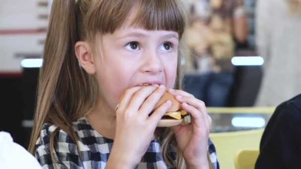 レストランでファーストフードを食べるかわいい子供の女の子 — ストック動画