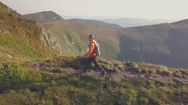 カルパチア山脈の山道を歩くオレンジ色のジャケットのバックパックを持つ観光ハイカー — ストック動画