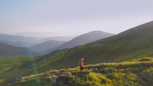 カルパチア山脈の山道を歩くオレンジ色のジャケットのバックパックを持つ観光ハイカー — ストック動画