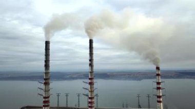 Kömür santralinden gelen gri dumanlı yüksek baca borularının havadan görüntüsü. Fosil yakıtla elektrik üretimi.
