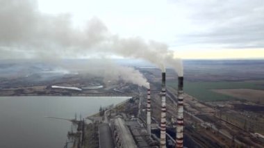 Kömür santralinden gelen gri dumanlı yüksek baca borularının havadan görüntüsü. Fosil yakıtla elektrik üretimi.