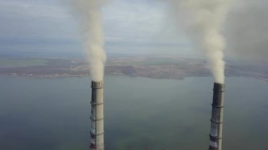 Kömür santralinden gelen gri dumanlı yüksek baca borularının havadan görüntüsü. Fosil yakıtla elektrik üretimi.