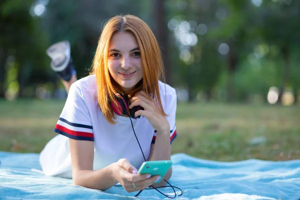 Bastante sonriente adolescente con el pelo rojo usando sellphone outdoo —  Fotos de Stock