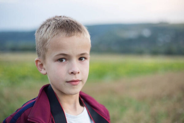 Portrait of a serious child boy outdoors.