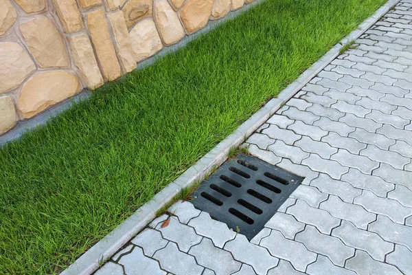 Gouttière de drainage en plastique, pelouse verte et trottoir en pierre sidewa — Photo