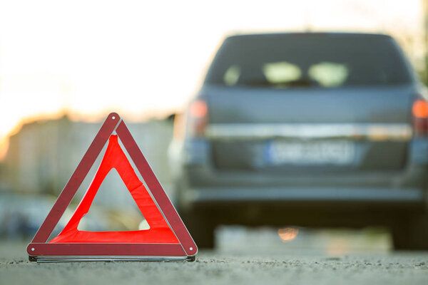 Красный аварийный треугольник знак остановки и сломанная машина на городской улице
