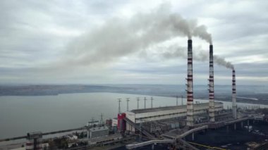 Kömür santralinden gelen gri dumanlı yüksek baca borularının havadan görüntüsü. Fosil yakıtla elektrik üretimi.