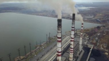 Kömür santralinden gelen gri dumanlı yüksek baca borularının havadan görüntüsü. Fosil yakıtla elektrik üretimi.