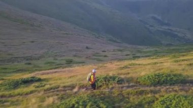 Sırt çantalı bir turist Carpathian dağlarında dağ yolunda koşuyor. Erkek turist kayalık çöl arazisinde koşuyor..