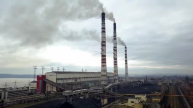 Kömür santralinden gelen gri dumanlı yüksek baca borularının havadan görüntüsü. Fosil yakıtla elektrik üretimi.