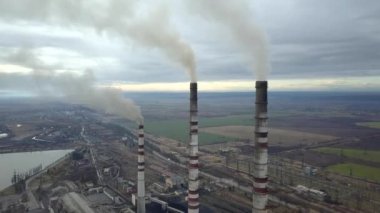 Kömür santralinden gelen gri dumanlı yüksek baca borularının havadan görüntüsü. Fosil yakıtla elektrik üretimi.