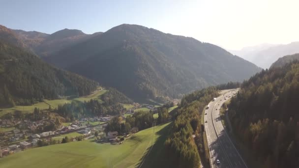 緑のフィールドとアルプスの山の間の農村部で高速移動交通と高速道路州間道路の空中ビュー — ストック動画