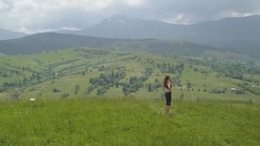 Genç kadın bir yaz günü dağ manzarasının tadını çıkarıyor. Doğa ortamında dinlenme ve meditasyon.