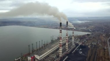 Kömür santralinden gelen gri dumanlı yüksek baca borularının havadan görüntüsü. Fosil yakıtla elektrik üretimi.