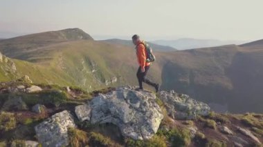 Karpat dağlarında dağ yolunda yürüyen turuncu ceketli bir sırt çantası ile Turist yürüyüşçü.